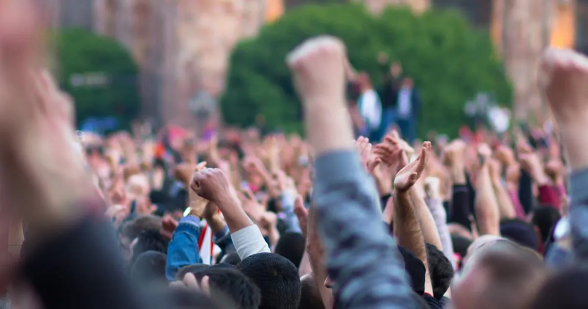 crowd protesting with hands in the air